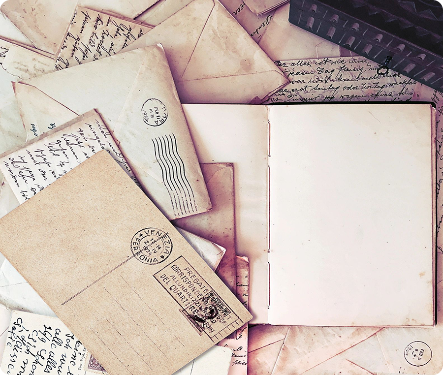 Overhead view of an open blank journal among old scattered letters and papers from the beginning of the 20th century.