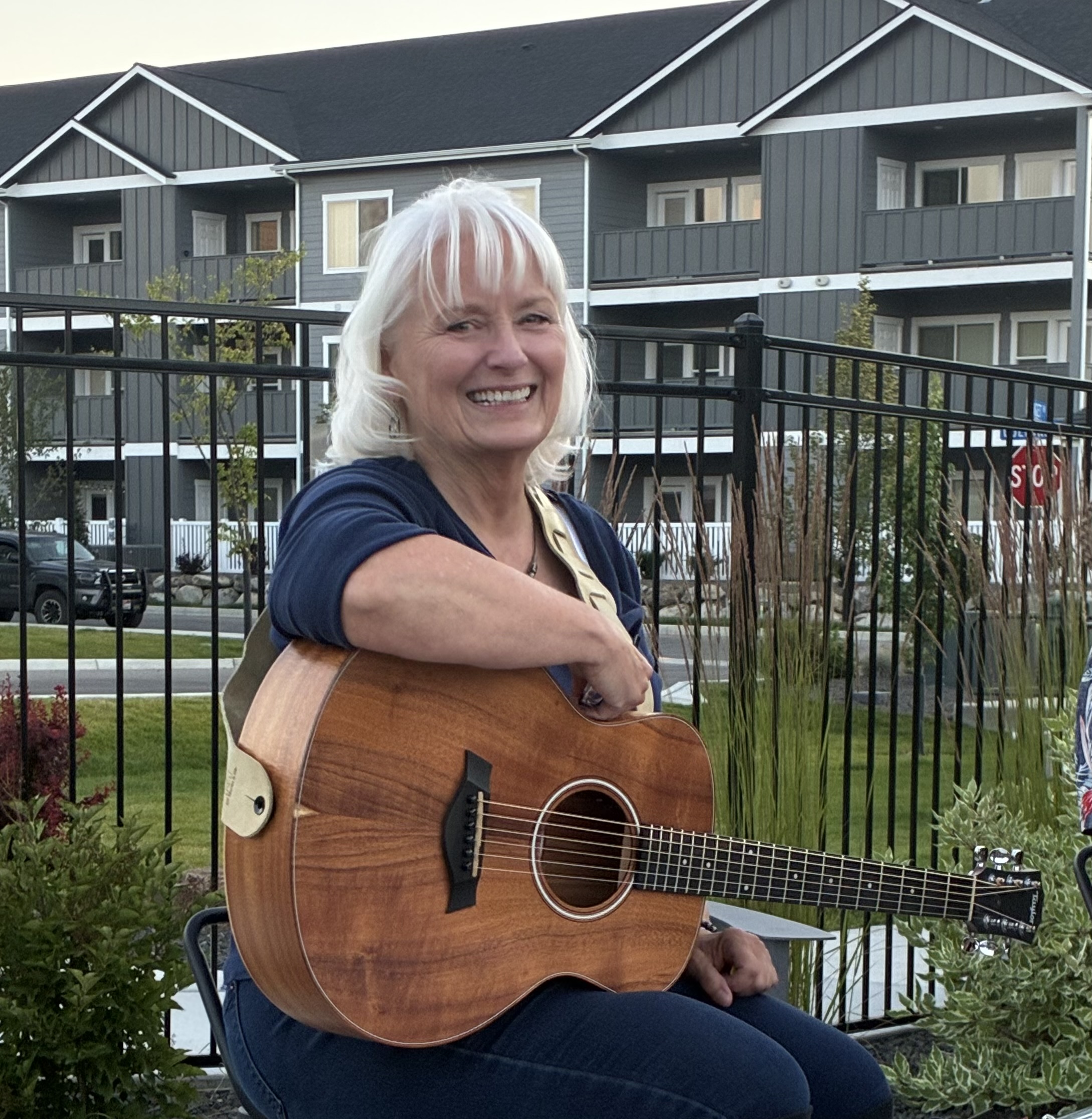Woman holding guitar near fence